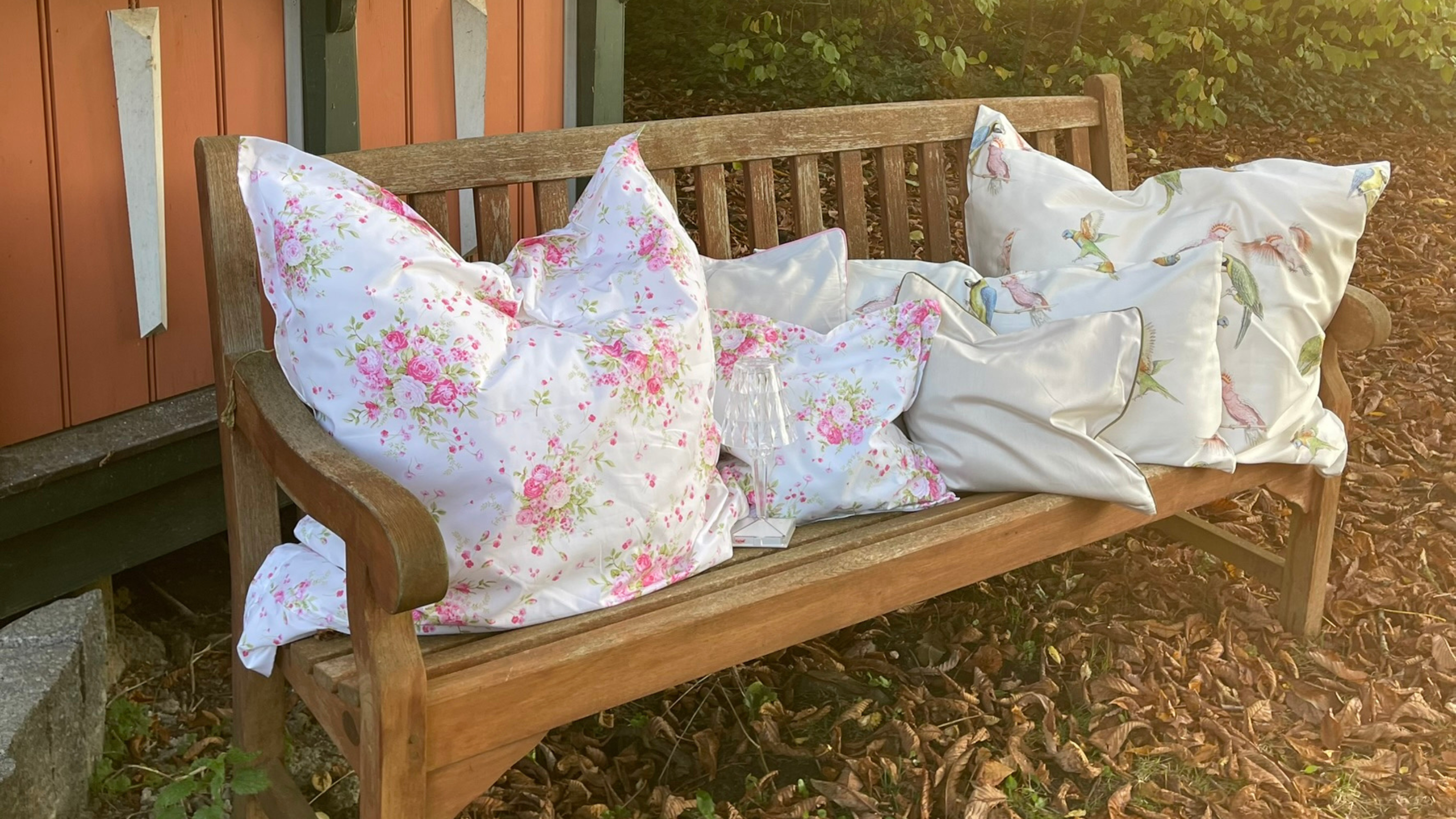 Mako-Satin Kissen und Deko-Kissen von LuxCocoon auf Holzbank arrangiert – florale Designs aus 100 % Baumwolle